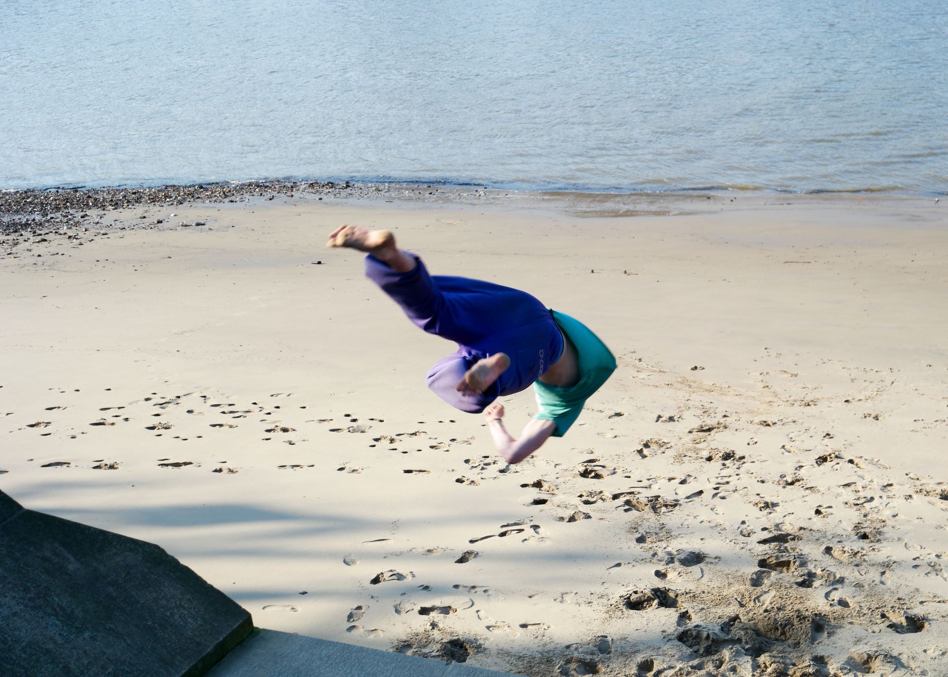 A freerunner leaping through the air above the sand on the South Bank in London