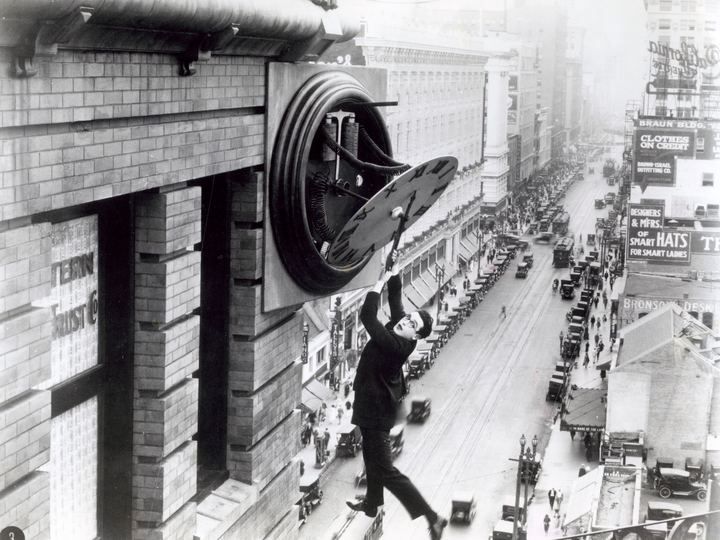 Harold Lloyd hanging from a giant clock above a city street in Safety Last